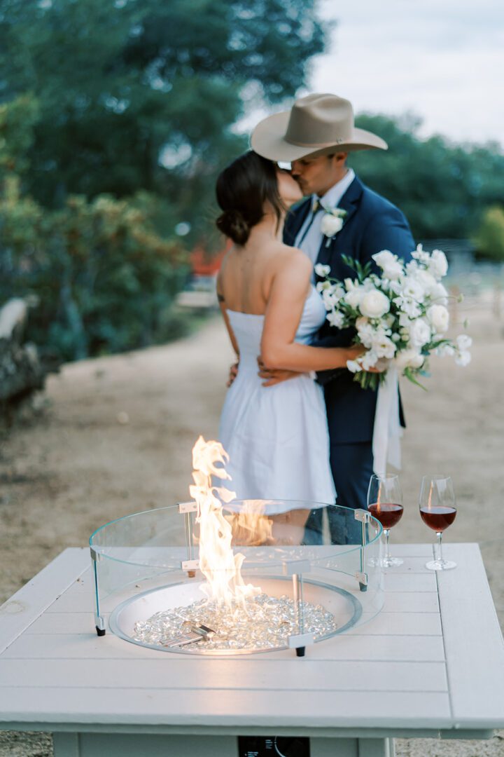 A couple embraces during a romantic outdoor celebration with sparklers and wine.