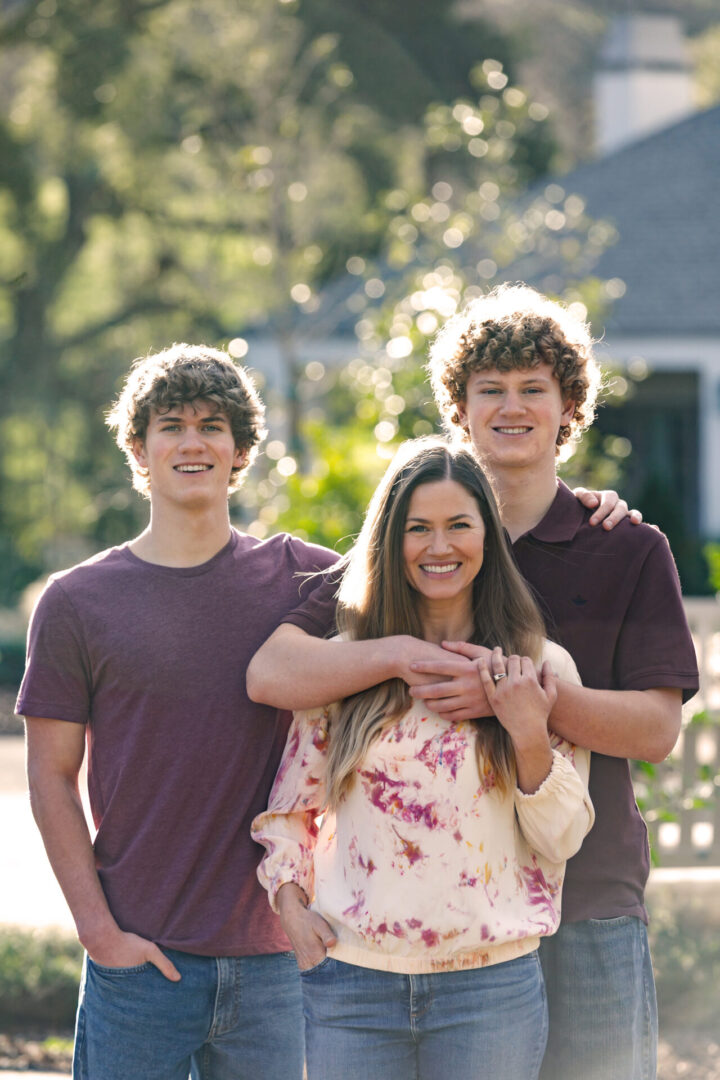 Three smiling teenagers posing outdoors in casual clothes.