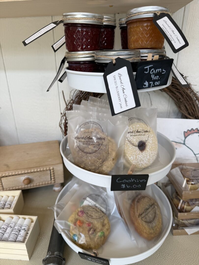 Three glass jars with cookies and labels on a white tiered stand.