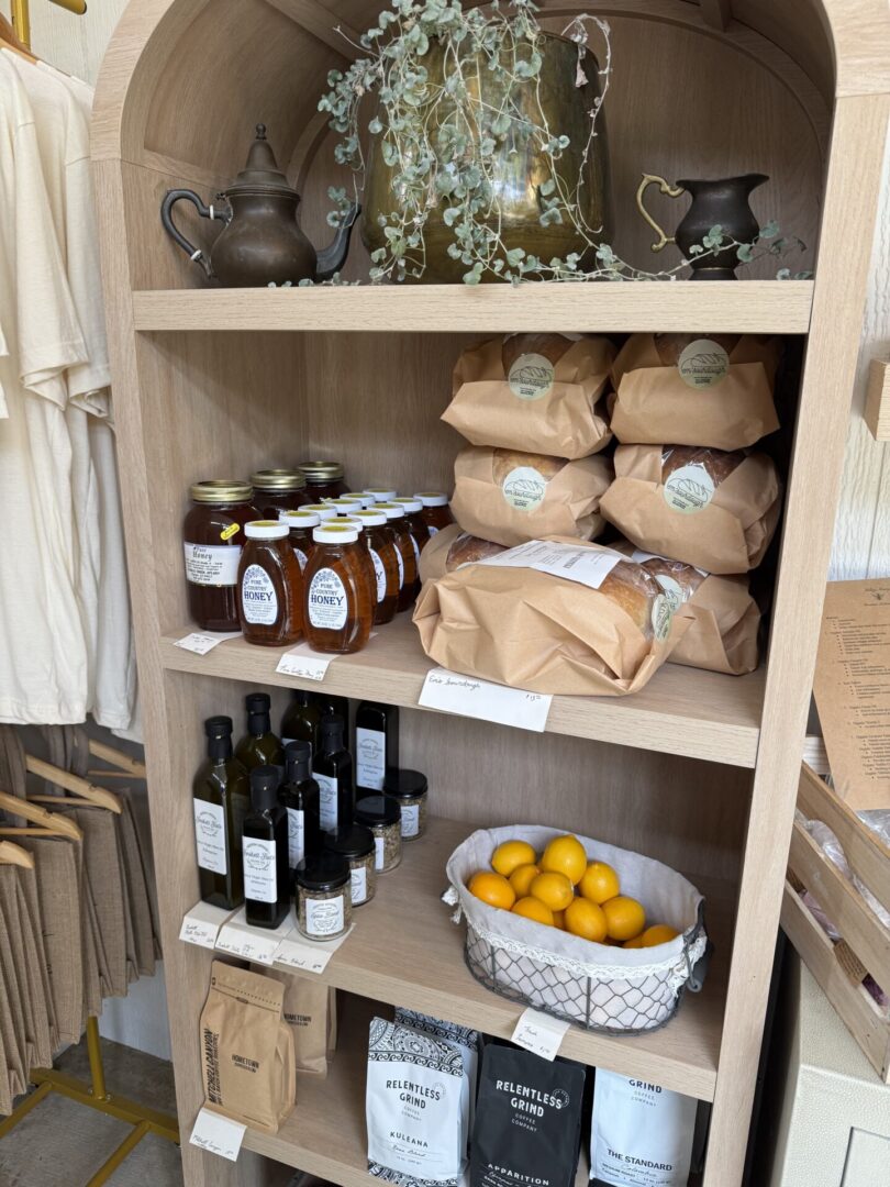 Wooden shelves stocked with jars, bags, bottles, and a bowl of lemons.