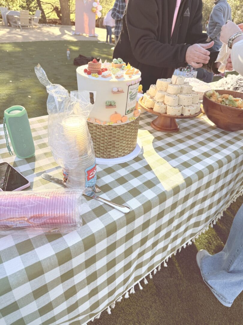 A picnic table with various snacks and drinks outdoors.