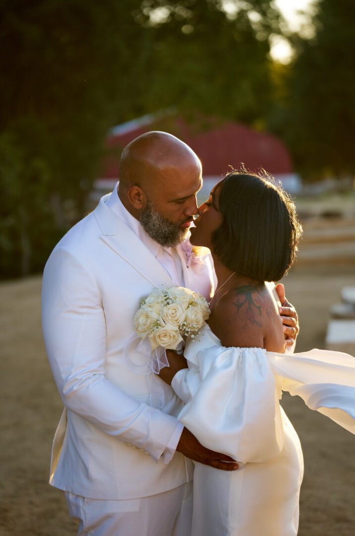 Newlyweds share an intimate moment outdoors at sunset.