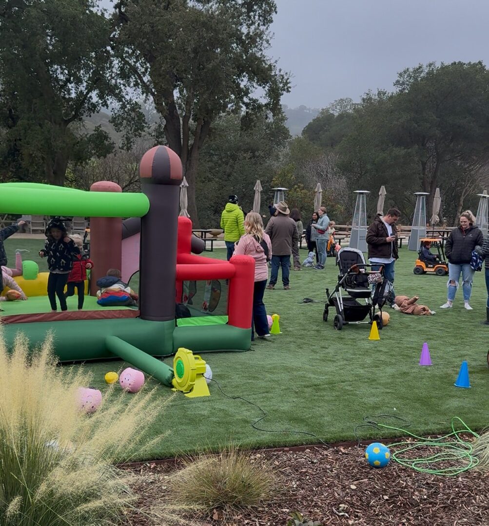 Children playing on an inflatable obstacle course outdoors.