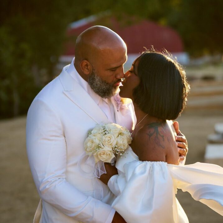 Newlyweds share an intimate moment outdoors at sunset.